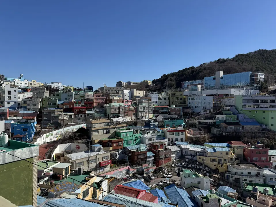 Busan's Gamcheon Culture Village — a hillside stacked with colorful houses under a blue sky.