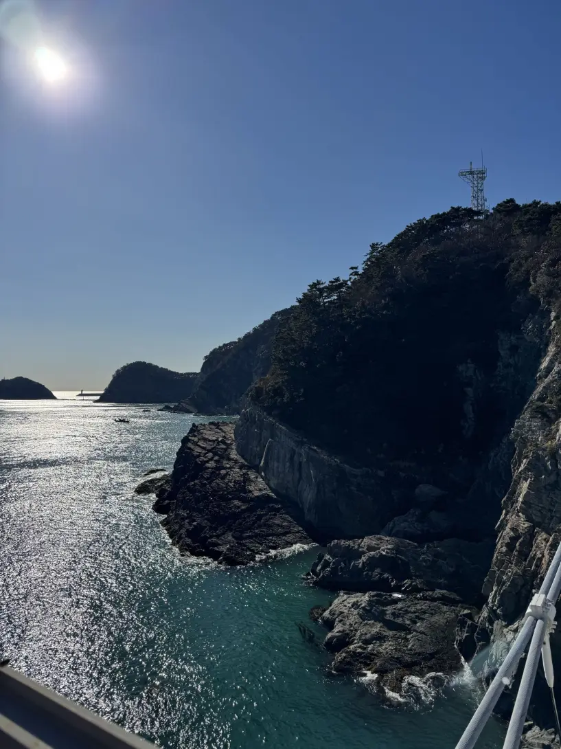 Bright sun over an emerald sea beside the cliffs.
