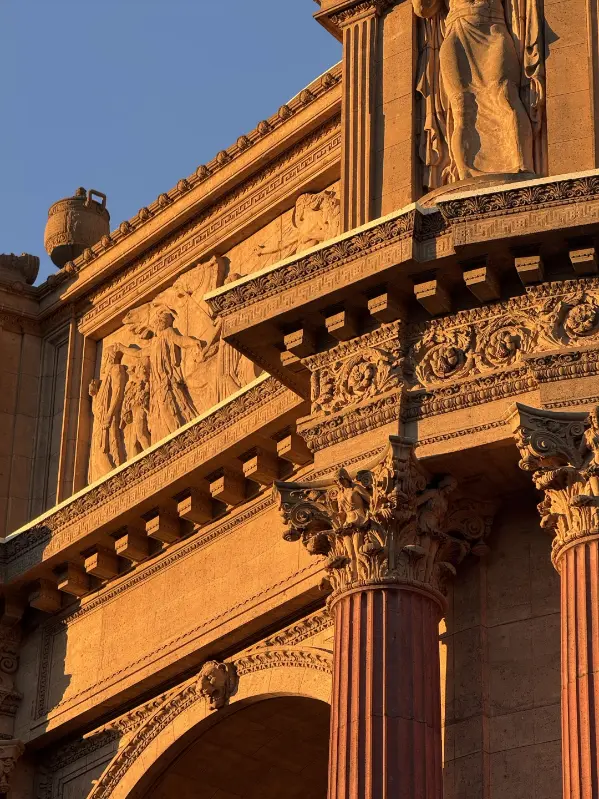 The Palace of Fine Arts colonnade glowing warm in golden-hour light against a blue sky.
